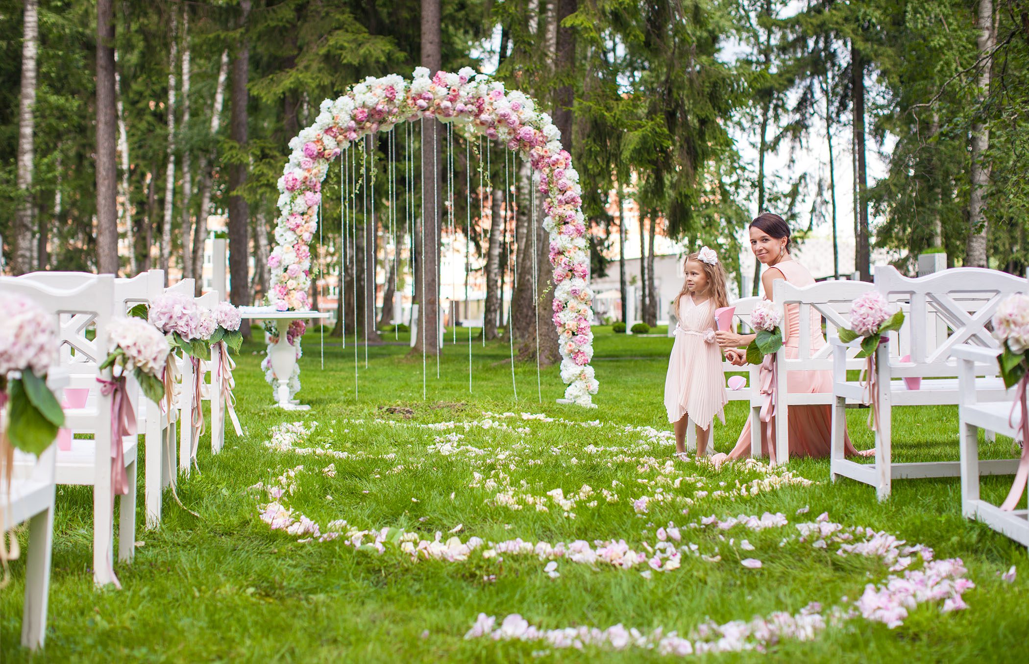 Wedding benches with guests and flower arch for ceremony outdoors